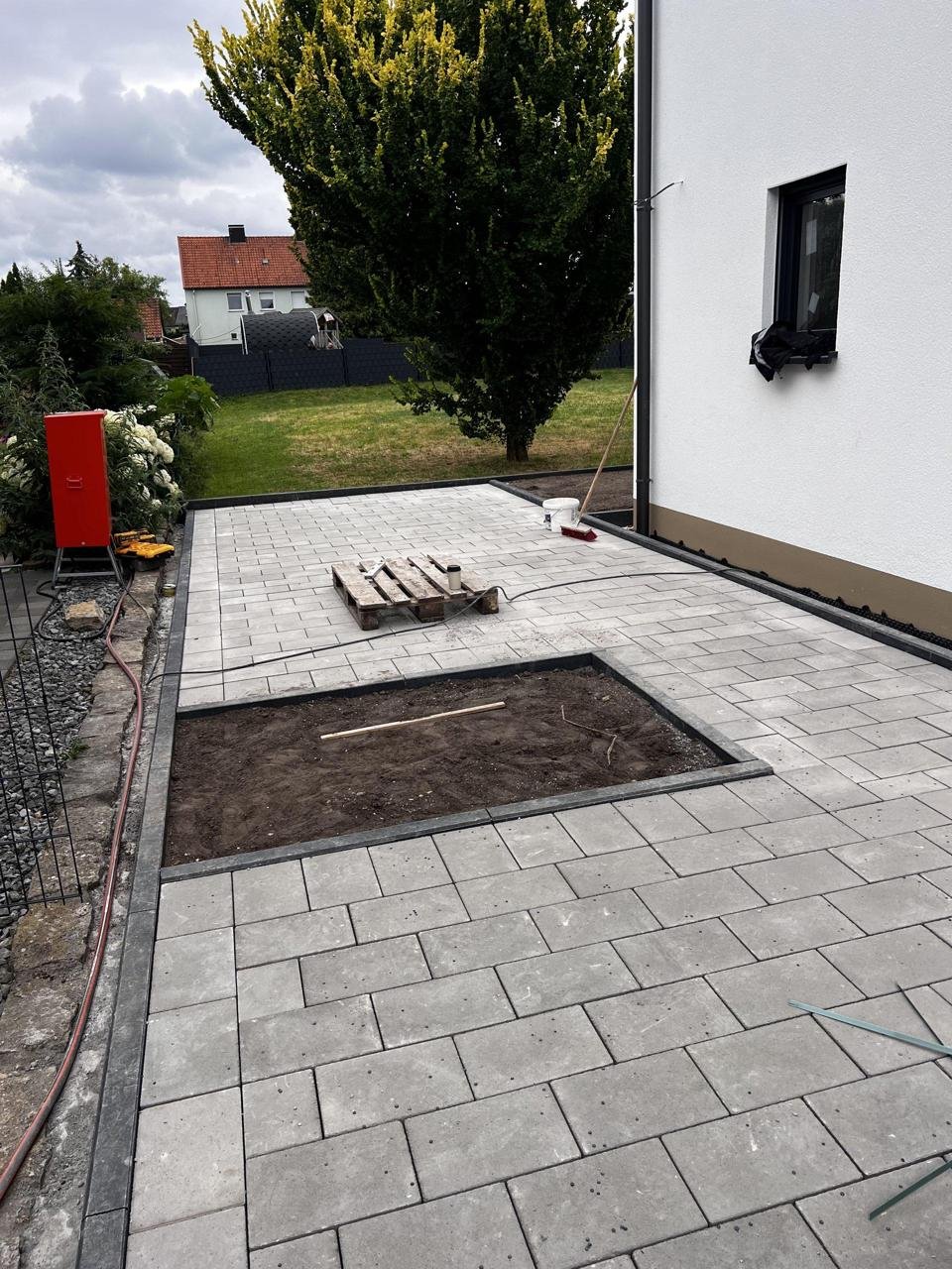 Gepflasterte Hoffläche mit ausgesparter Fläche an einem Wohnhaus