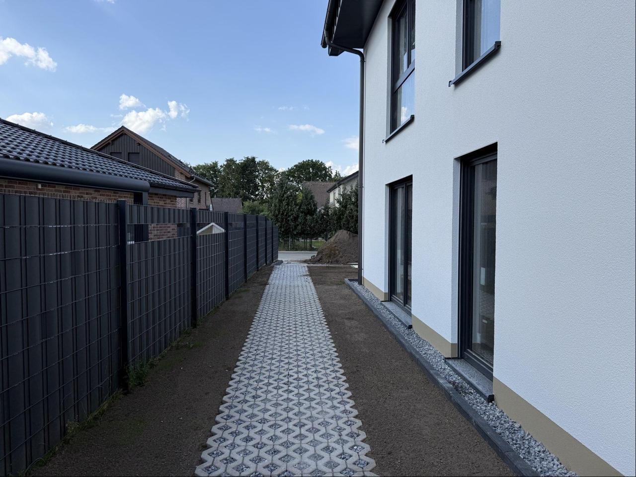 Schmaler Pflasterweg mit Ornamentsteinen entlang einer Hausfassade