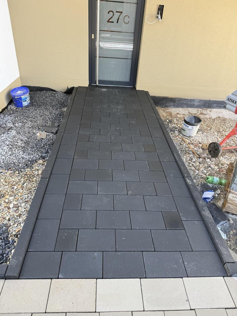 Gepflasterter Hauseingang mit anthrazitfarbenen Platten